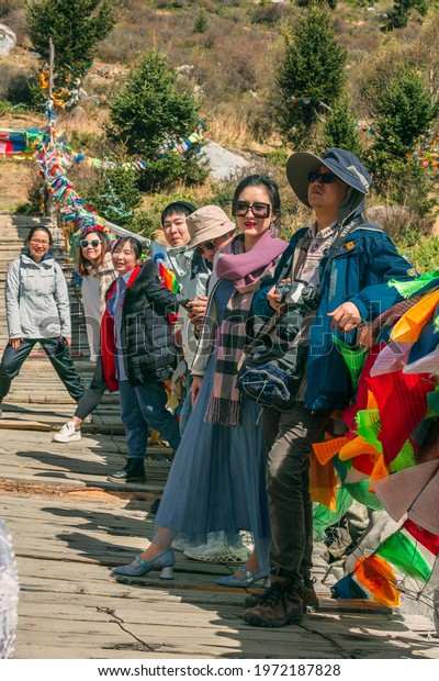 TIBET,
CHINA, MAY 2021: Traveler walks under colorful prayer flags while
crossing a rope bridge in the Tibetan
wilderness