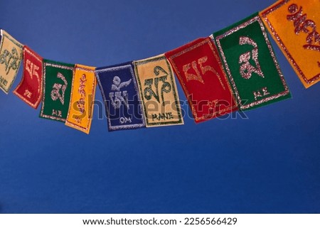 Tibetan Buddhist flags against blue background. Text on flags Om mani padme hum meaning The jewel is in the lotus.
