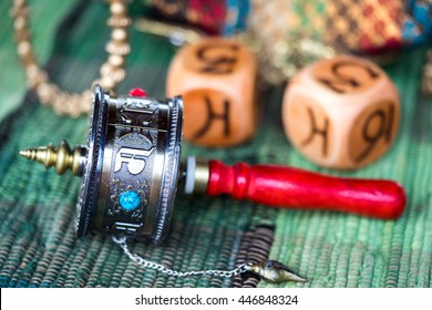 A Tibetan Prayer Wheel to increase good and get rid of bad karma laying on the table with dice