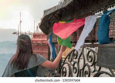Tibetan prayer wheels. A woman tourist rolling the prayer wheels at Swayambhunath, Nepal. Text translation: The magic symbol power of buddhism for prayer get divine blessings and good fortune
