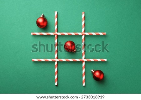 Tic tac toe game made with Christmas balls on green background, flat lay