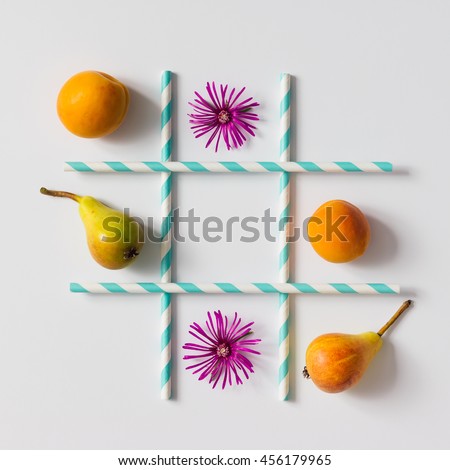 Tic tac toe made of  fruits, flowers and straws. Flat lay. Healthy food concept.