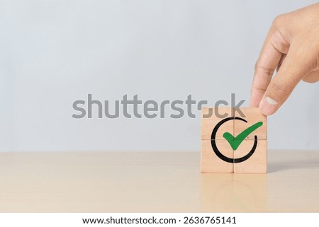 Tick mark icon on cube block being assembled by hand. Symbol of project approval, certified documents, and quality control process