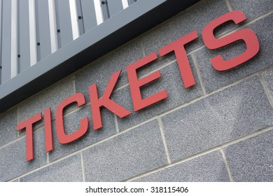 Tickets sign in red on the grey exterior wall of a sports stadium.