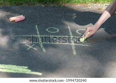 Tic-tac-toe chalk game on asphalt, drawing on the sidewalk.