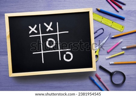 Tic-Tac-Toe on the school board. Game of Noughts and Crosses played on chalk board. Educational games for kids. Concept break time in school and business. Mind training, brainstorming.