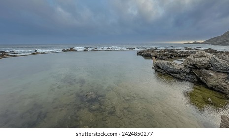 Tidal pool with dark clouds in background in Herolds Bay, close to George in the Garden Route in Western Cape South Africa