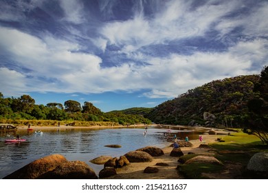 Tidal River at Wilson Promontory with autumn maple tree and blue cloudy sky view, people playing in the water