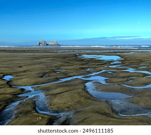 Tide pools reflecting the sky with the arch rock formation in the background at Rockaway Beach.  - Powered by Shutterstock