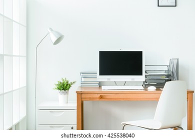 Tidy home office with wooden table and white computer on it. Bright room with white walls - Shutterstock ID 425538040