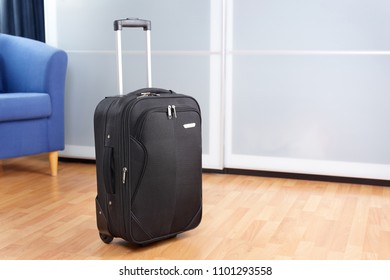 Tidy Room With Packed Roller Suitcase In Front Of Closet