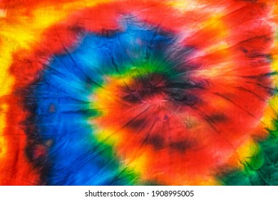 The tie dye spiral pattern on the fabric is hand-made. White clothes painted by hand. Flat lay.