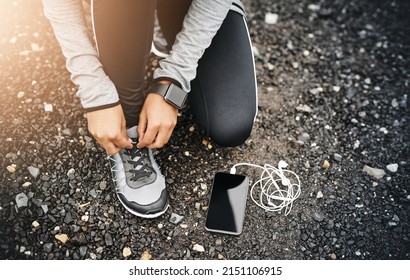 Tie those laces and get moving. Closeup shot of a sporty woman tying her shoelaces while exercising outdoors. - Powered by Shutterstock