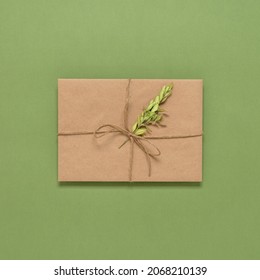 Tied Brown Envelope With Dry Boxwood Branch On Green Olive Paper Background. Top View, Flat Lay. Vintage Letter. Textured Object