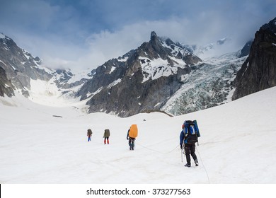 Tied Climbers Climbing Mountain With Snow Field