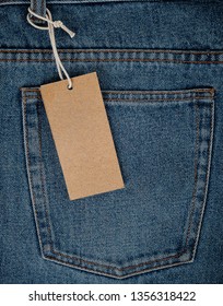 tied on a rope is an empty rectangular brown paper tag on blue jeans, full frame