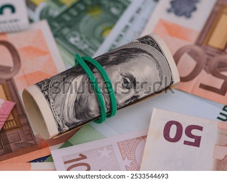 Tied stack of one hundred dollar bills lying on euro bills background.