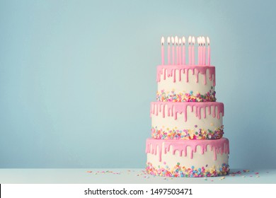 Tiered birthday cake with drip frosting and twelve candles - Shutterstock ID 1497503471