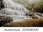 Tiers of cascading water over rocks into a shallow pool at its base