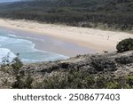 tiers of ocean waves breaking on golden sand beaches in a quiet cove viewed from rocky headlands above