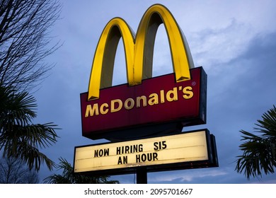 Tigard, OR, USA - Dec 23, 2021: McDonald's Sign With Hiring Ad Promising Hourly Minimum Wage Is Seen In The Evening At One Of Its Locations In Tigard, Oregon, During The Winter Holiday Season.