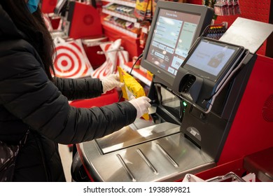 Tigard, OR, USA - Feb 21, 2021: A masked shopper in nitrile gloves scans a bag of Ricola cough drops at the self-checkout lane in a Target store in Tigard, Oregon.