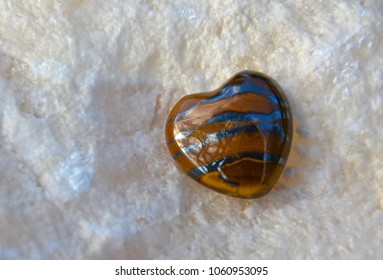 Tiger Eye Crystal Shaped Like A Heart On A White Onyx Stone.
