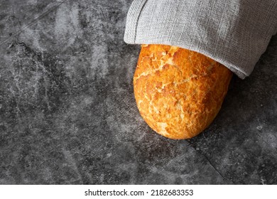 Tiger Loaf Of Bread Wrapped In A Grey Tea Towel. On A Black Stone Background