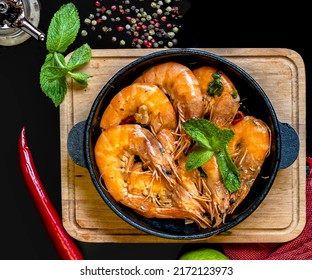 Tiger prawns fried in sauce. Ingredients - tiger prawns, garlic, soy sauce, Worcestershire sauce, oyster sauce, lime juice, chili pepper, olive oil, mint sprigs.
