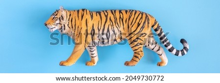 the tiger, symbol of 2022 year. plastic orange toy figure tiger on a blue background. top view. banner