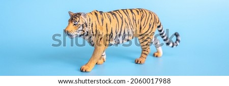 the tiger, symbol of 2022 year. plastic orange toy figure tiger on a blue background. banner
