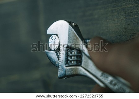 Tightening a bolt with an adjustable wrench. Tightening a stainless steel lag bolt with a wrench. 