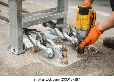 Tightening of bolts nuts screw washer in concrete surface. Cable tensioning. Installation of support in crash barriers on highway. Bridge construction. Metal road fencing on freeway. Road guard rails.