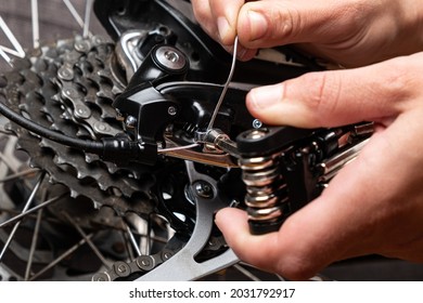 tightening the gear shift cable on a bicycle with multitool. - Shutterstock ID 2031792917