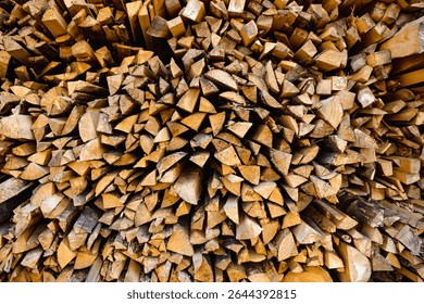 Tightly packed pile of split firewood arranged in an organic pattern, with earthy textures revealing freshly chopped surfaces of the wood, ready for seasoning or immediate use as fuel