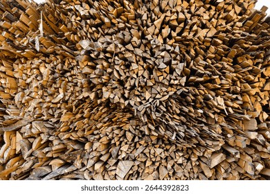 Tightly packed pile of split firewood arranged in an organic pattern, with earthy textures revealing freshly chopped surfaces of the wood, ready for seasoning or immediate use as fuel
