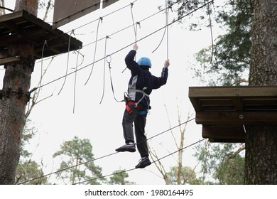 Tightrope walker boy in helmet and safety equipment on European outdoor forest rope park at spring summer day - climbing sports active recreation - Powered by Shutterstock