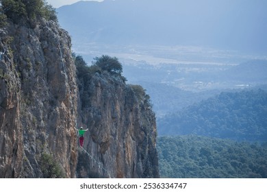 A tightrope walker walks along a cable stretched over a canyon. - Powered by Shutterstock