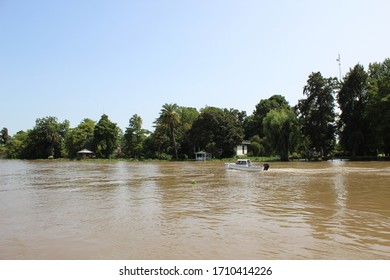 Tigre Delta In Argentina, River System Of The Parana Delta North From Capital Buenos Aires. Lush Vegetation, Traditional Wood House By Wooden Pier And Orange Water That Carry Clay To Rio De La Plata.