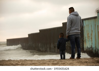 Tijuana, Baja California, Mexico - April 11, 2021: A father and son stand in front of the USA Mexico border wall.