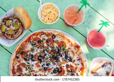 Tiki Bar Food Spread With Pizza, Mac & Cheese, Pulled Pork And Cocktails On Green Background