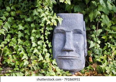 A tiki stone head in the vines to the side of the growth