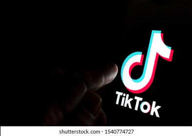 TikTok app logo on screen and a finger pointing at it.  Concept for app being in spotlight- blame, antitrust, regulation, child privacy, lawsuit, security. Stafford, United Kingdom - July 28 2019