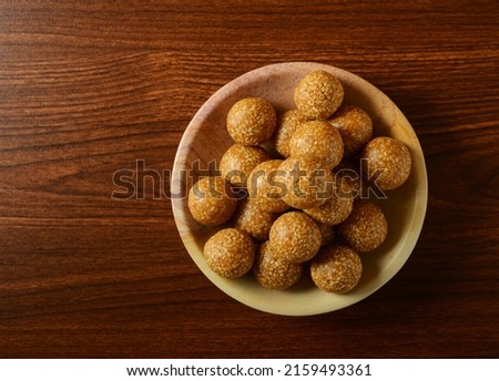 Til Laddu served in a bowl on wooden background. Nutritious and healthy Indian traditional sweet.