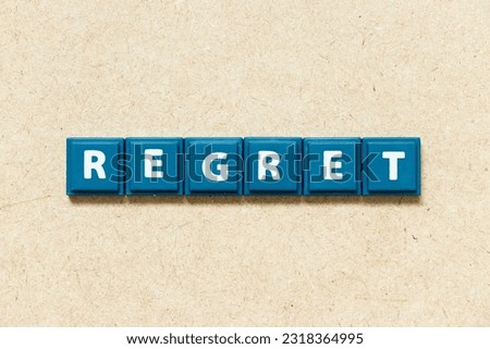 Tile alphabet letter in word regret on wood background