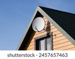 Tile roof antenna background. TV satelite dish old house roof. Countryside village architecture rooftop satelite. Television antenna mount. Orange wood house facade with mounted satellite.