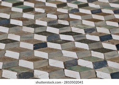 A tiled pattern entryway to an uncovered house in Pompeii Italy shows an illusion of depth to the otherwise flat tiles in shades of grey.