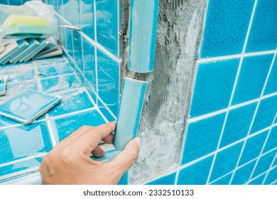 Tiled pool. The man hand while using spacer for installing tiles. construction work.Construction Pool.Technicians are tiled swimming pool.