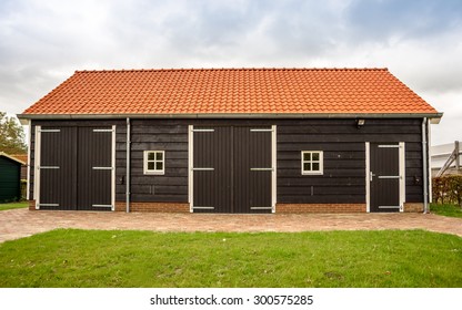 A tiled roof wooden outhouse with a lawn of fresh green grass in front of it - Powered by Shutterstock