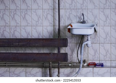 Tiled wall in a car wash garage. Sink for washing hands and rusty batteries. Water supply and sewerage system in the production area. No people. Copy space.